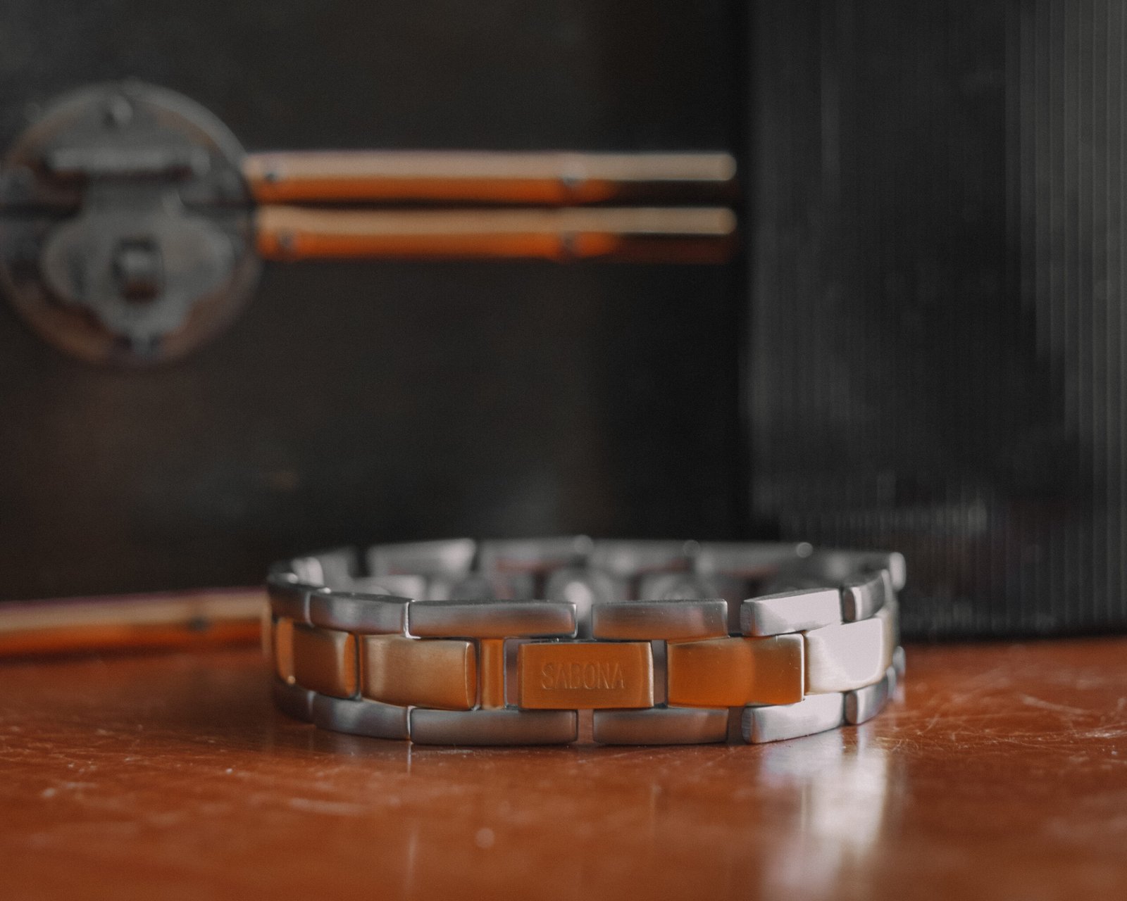 Bracelet bicolore en acier présenté sur du bois sombre